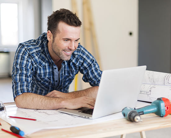 Man on a computer purchasing equipment from Cardinal Leasing using shed trailer financing.